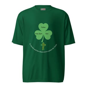 Puede incluir: Camiseta verde con un diseño de trébol. El trébol tiene las palabras "Padre", "Espíritu Santo" e "Hijo". Debajo hay una cruz celta y el texto "San Patricio usó el trébol para explicar la Trinidad."