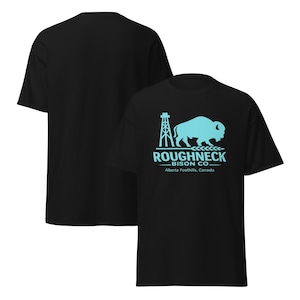 May include: Black t-shirt featuring a turquoise graphic of a bison, oil derrick, and text that reads "ROUGHNECK BISON CO. Alberta Foothills, Canada." The shirt has a crew neck and short sleeves.