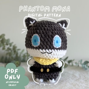 May include: A crochet plush toy featuring a dark gray head with white lower face, bright blue eyes, and pointed ears. It wears a yellow neck scarf and a black belt with gold accents. Text reads PHANTOM MONA DIGITAL PATTERN PDF ONLY.