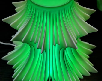 May include: A green, layered, tree-shaped lamp with a bright, glowing interior. The lamp has a series of pointed, fan-like layers that create a unique design. The lamp is illuminated with a bright green light, creating a soft glow.