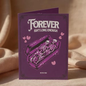 Puede incluir: Una tarjeta de felicitación morada con el texto "FOREVER ISN'T LONG ENOUGH" en escritura blanca. La tarjeta presenta una ilustración de dos esqueletos en un ataúd, con corazones rosas. Las palabras "WITH YOU" están en la parte inferior.