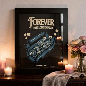 Puede incluir: Impresión artística enmarcada en negro con el texto "Forever Isn't Long Enough". La obra presenta dos esqueletos en un ataúd con acentos de corazón. La parte inferior de la impresión tiene espacio para nombres personalizados. La impresión se muestra sobre una superficie de madera oscura.