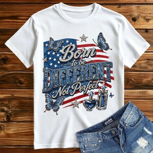 Op de afbeelding: Een wit t-shirt met korte mouwen voorzien van een afbeelding van een Amerikaanse vlag, vlinders en twee parfumflesjes. De tekst luidt Born to be DIFFERENT Not Perfect. Het ontwerp bevat blauwe, rode en witte kleuren met sterren.