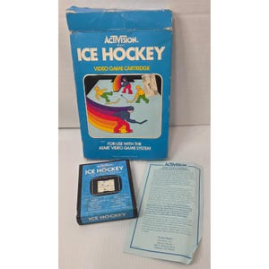 Puede incluir: Un cartucho de videojuego Activision Ice Hockey vintage para el sistema Atari. La caja azul presenta el título del juego y un gráfico colorido de jugadores de hockey. Incluye el cartucho del juego y una hoja de garantía.