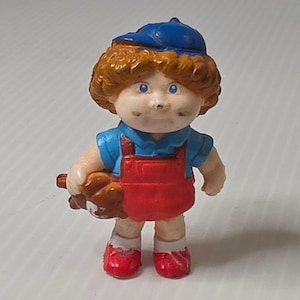 Figurina in PVC Cabbage Patch Kids, piccola, rossa e blu, edizione speciale Panini OAA del 1984.