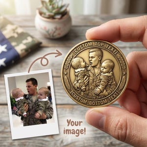 May include: A gold-colored coin held by a hand, featuring a detailed relief of a person holding two babies. The coin has text that reads "[CUSTOM TOP TEXT]", "[CUSTOM DATE]", and "[CUSTOM BOTTOM TEXT]" around the edges. A photo of the same scene is shown.
