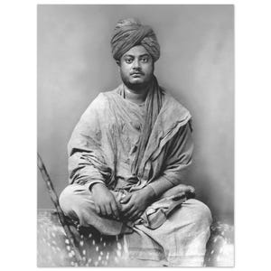 May include: Black and white portrait of a man seated cross-legged, wearing a turban and draped in a shawl. The image is a medium shot, capturing the subject's upper body and the details of his attire.