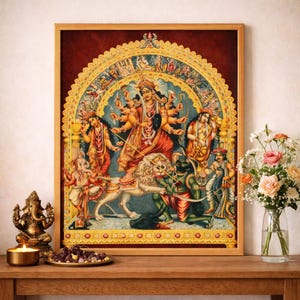 Puede incluir: Una impresión enmarcada de una deidad hindú, con una figura central con múltiples brazos, montada sobre un león. La obra de arte tiene un diseño detallado y colorido con detalles dorados, sobre un fondo rojo oscuro. Una pequeña estatua dorada y una vela están frente al marco.