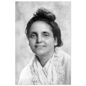 Puede incluir: Retrato en blanco y negro de una mujer con cabello oscuro recogido en un moño. Lleva una prenda blanca y una guirnalda de flores alrededor del cuello. La fotografía es un primer plano, mostrando su rostro sonriente.