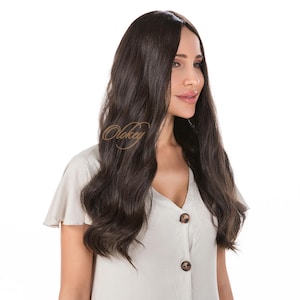 Op de afbeelding: Een lange, golvende, donkerbruine pruik. De pruik is gestyled met losse golven en heeft een natuurlijk ogende haarlijn. Het model draagt een lichtgekleurd overhemd met knopen. De merknaam "Olokey" is zichtbaar op de afbeelding.