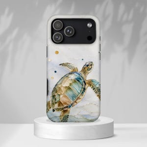 Può includere: Una custodia per smartphone con un'illustrazione di una tartaruga marina con effetto vetrata in tonalità blu, verde e marrone. Lo sfondo presenta un motivo in marmo bianco con sottili linee dorate e piccoli accenti circolari dorati e blu scuro.