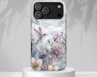 May include: A smartphone case featuring a winter landscape with a hummingbird in flight, surrounded by soft-toned purple and white flowers, delicate berries, and gold-accented foliage against a snowy, marble-like background with a triple camera cutout.