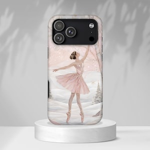 May include: A smartphone case featuring a printed illustration of a ballerina in a pink tutu dancing in a snowy landscape with pine trees. The design includes soft pink and white tones with gold accents, set against a winter backdrop.