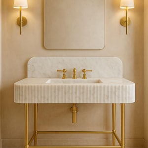 Puede incluir: Un elegante mueble de baño con un lavabo de mármol y grifos dorados. El lavabo tiene un diseño acanalado y se apoya sobre una estructura de metal dorado. Un espejo rectangular y dos apliques completan el conjunto.