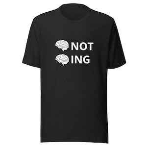 May include: Black t-shirt with the white text "NOT ING" and two white brain illustrations. The shirt is made of a soft material and has short sleeves. The design is centered on the front of the shirt.