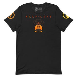 Könnte beinhalten: Schwarzes T-Shirt mit dem roten Schriftzug "HALF-LIFE" und einer orange-schwarzen Grafik einer Schutzweste. Die Ärmel zeigen orangefarbene und gelbe Logos. Ein kleines Etikett ist in der Nähe des Halsausschnitts sichtbar.