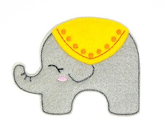May include: A gray felt elephant with a yellow felt saddle and pink eyes. The elephant is smiling.