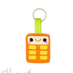 May include: Orange felt calculator keychain with a smiling face and a green ribbon loop.