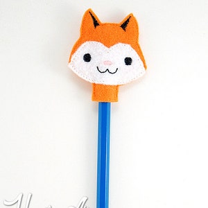 May include: A felt fox pencil topper with a white face, black eyes, and a pink nose. The topper is attached to a blue pencil.