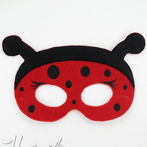 May include: Red ladybug mask with black spots and antennae. The mask has eye holes and black felt around the edges.