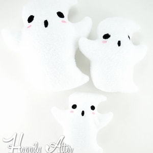 Op de afbeelding: Drie witte pluche spookjes met zwarte ogen en roze wangen. De spookjes zijn van verschillende grootte, met het grootste spookje bovenaan de afbeelding en het kleinste spookje onderaan.