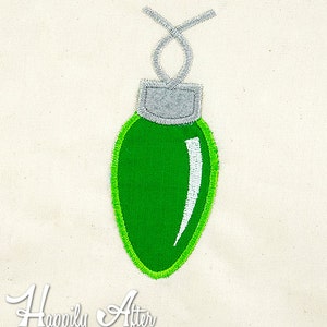 May include: A green Christmas light ornament with a white highlight and a silver loop.