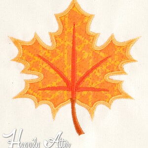 May include: Orange and yellow embroidered maple leaf with a brown stem. The leaf has a textured, speckled design.