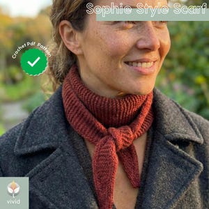 May include: A rust-colored knitted scarf tied at the neck. The scarf is worn over a gray coat. The image includes the text "Sophie Style Scarf" and a "Crochet Pdf Pattern" logo.