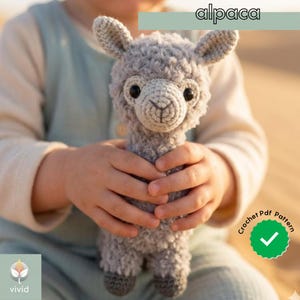May include: A gray crocheted alpaca plush toy with black eyes and a detailed face. The alpaca is held in a child's hands. The image includes the text "alpaca" and "Crochet PDF Pattern".