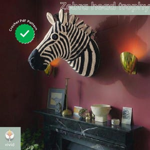 May include: A black and white crocheted zebra head trophy displayed on a wall. The trophy features a detailed striped pattern and a textured finish. The text "Zebra head trophy" is at the top of the image. A green circle with a checkmark and the words "Crochet Pdf Pattern" is in the upper left corner.