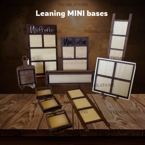 May include: A selection of wooden mini bases in different forms. Some have a light wood interior with a dark wood frame, others have a dark wood exterior. The word "Welcome" is displayed on two of the bases. The bases are on a wooden surface.