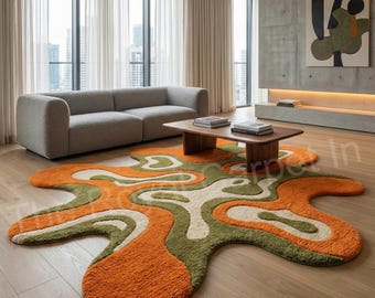 Könnte beinhalten: Ein moderner Teppich in organischen Formen mit orangefarbenen, grünen und cremefarbenen Mustern. Er liegt auf einem Holzboden in einem Wohnzimmer mit einem grauen Sofa und einem Holztisch.