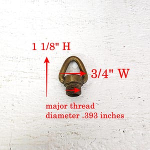 May include: A brass-colored eye bolt with a threaded base. The eye bolt is 1 1/8 inches high and 3/4 inches wide. The major thread diameter is .393 inches. The eye bolt is designed for hanging or securing items.