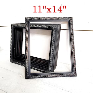 May include: Black picture frames, 11" x 14", with a textured, rope-like design around the edges. Several frames are stacked together, showcasing the depth and style of the frames. The frames are a dark color, with a hint of brown.