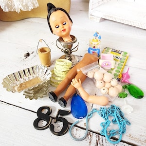 May include: Assortment of vintage and handmade items including a doll head, doll limbs, a small wooden bucket, a measuring tape, a plastic castle, a bag of beads, a blue glass teardrop, a blue chain, and the numbers 8 and 5.