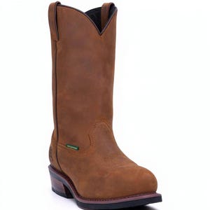Puede incluir: Una bota de vaquero de cuero marrón con punta y tacón apilado. La bota tiene una etiqueta impermeable y un diseño sin cordones. La bota mide aproximadamente 30 cm de alto.