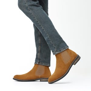 Peut inclure: Bottes Chelsea en daim marron clair avec des empi&egrave;cements lat&eacute;raux &eacute;lastiques et un petit talon. Les bottes sont port&eacute;es avec un jean bleu. Design classique et minimaliste.