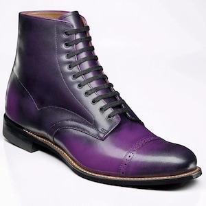May include: A purple leather boot with black laces. The boot features a cap toe with decorative perforations and a black sole. The leather has a gradient effect, transitioning from a darker shade at the top to a vibrant purple at the toe.