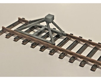 Peut inclure: Maquette de voie ferrée miniature avec une structure métallique grise. La voie est composée de traverses en bois marron et de rails en métal foncé. La structure grise, de conception géométrique, est centrée.
