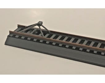 Könnte beinhalten: Ein Miniatur-Modellgleisabschnitt. Die Strecke hat dunkelgraue Schienen und braune Schwellen mit einer dunkelgrauen Basis. Eine kleine, dunkelgraue Überkopfstruktur ist ebenfalls vorhanden.