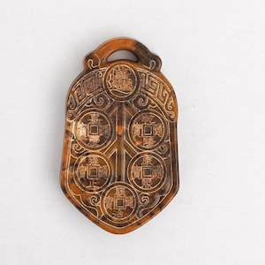 May include: A brown, ornate pendant with a loop at the top. The pendant features six circular designs with Chinese characters and intricate patterns. The overall design is symmetrical and detailed, with a vintage aesthetic.