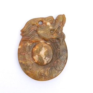 May include: A carved jade pendant in shades of green and brown, featuring a dragon head at the top and a central circular design surrounded by coin-like shapes. The pendant has a hole for hanging.