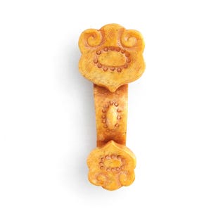 May include: A carved, antique-looking, yellow-beige ornamental object. The object has a floral design on both ends and a central, elongated stem. The floral designs feature a series of small, circular indentations. The object is likely made of stone or a similar material.