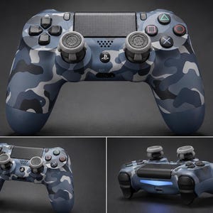 Può includere: Un controller per videogiochi wireless con un motivo mimetico blu, grigio e nero. Il dispositivo include due levette analogiche grigie, un touchpad centrale, il logo PlayStation e pulsanti di azione con icone triangolo, cerchio, croce e quadrato.
