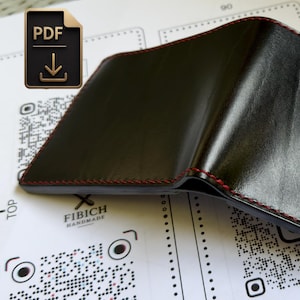 Könnte beinhalten: Ein schwarzes Leder-Bifold-Portemonnaie mit auffälligen roten Nähten entlang der Kanten. Das Portemonnaie hat eine glatte, polierte Oberfläche und ist aufgeklappt dargestellt, was die Verarbeitung und den Kontrast der Farben zeigt.