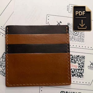 May include: A rectangular leather card holder featuring alternating horizontal stripes of dark brown and tan leather. The item is constructed with visible light-colored stitching along the edges and across the center, creating a structured design.