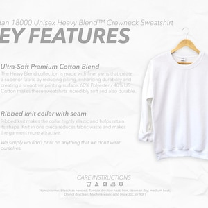 May include: A white Gildan 18000 Unisex Heavy Blend crewneck sweatshirt hanging on a wooden hanger. The image includes text highlighting key features: Ultra-Soft Premium Cotton Blend and Ribbed knit collar with seam. Care instructions are also visible.