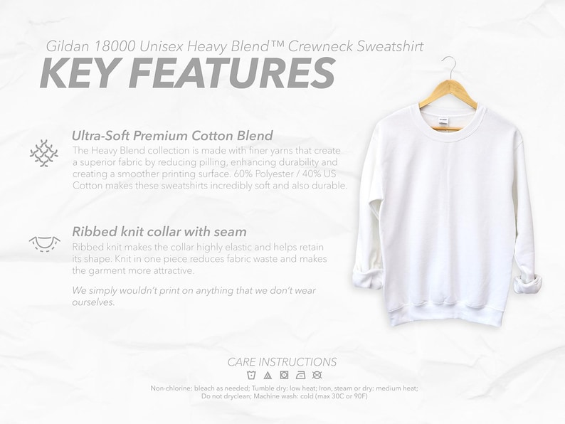 May include: A white Gildan 18000 Unisex Heavy Blend crewneck sweatshirt hanging on a wooden hanger. The image includes text highlighting key features: Ultra-Soft Premium Cotton Blend and Ribbed knit collar with seam. Care instructions are also visible.