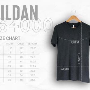 May include: Dark gray Gildan 64000 t-shirt hanging on a wooden hanger. A size chart shows measurements in inches for width, chest, and length, ranging from XS to 4XL. The shirt's chest, length, and width are labeled.