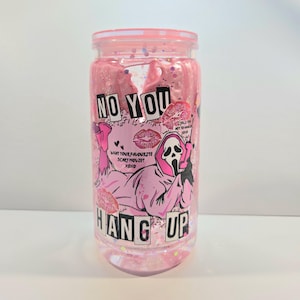 May include: A pink, clear tumbler with a screw-on lid. The tumbler features a pink graphic of the Ghostface character from the movie Scream, with the words "NO YOU HANG UP" and "WHAT YOUR FAVORITE SCARY MOVIE? XOXO".